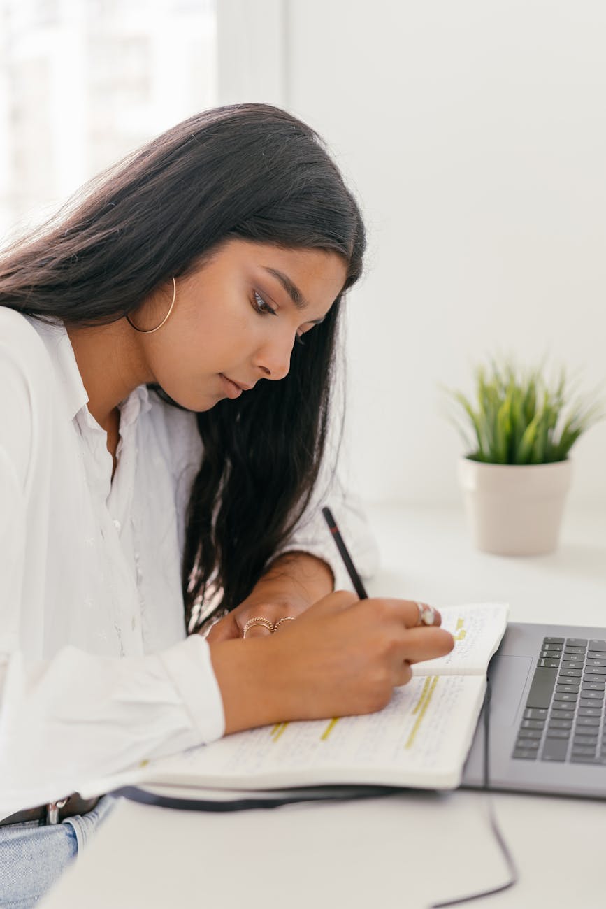 woman in white dress writing into the notebook