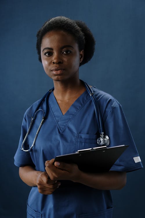 Healthcare worker in scrubs holding clipboard