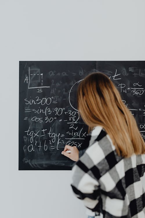 Teenage girl solving maths on chalkboard