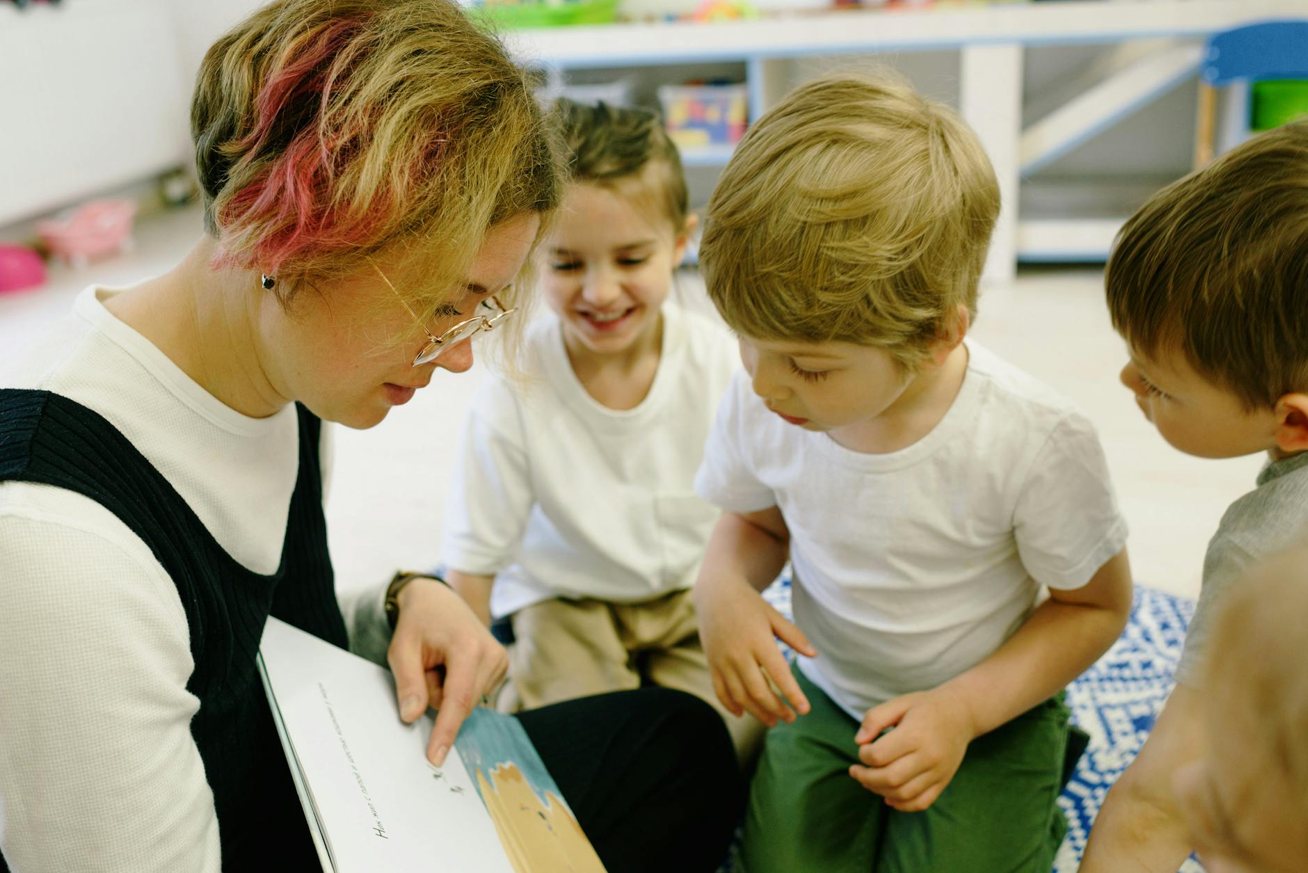 Nursery worker reading with young children