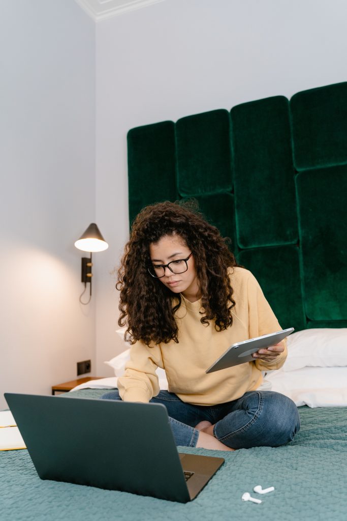 Lady sitting on bed studying on a laptop